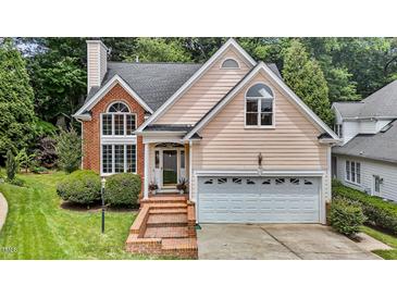Charming home featuring a two-car garage and brick accents with manicured landscaping at 6728 Pointe Vista Cir, Raleigh, NC 27615