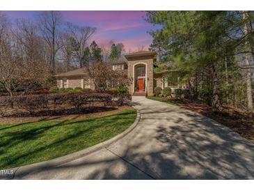 Beautiful brick home with well-manicured landscaping, long driveway, and red front door at 10210 Governors Drive Dr, Chapel Hill, NC 27517