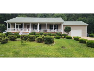 Charming ranch-style home featuring a metal roof, covered porch, and meticulously manicured front yard at 107 Oak Park Dr, Benson, NC 27504