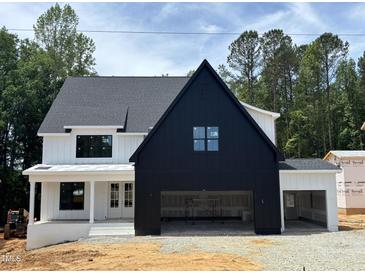 Striking two-story home showcasing a modern farmhouse design with a bold black garage and complementary white siding at 2391 Herbert Akins Rd, Fuquay Varina, NC 27526