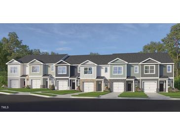 A row of modern townhomes features a clean design and manicured landscaping in a suburban setting at 5215 Red Crimson Dr, Willow Springs, NC 27592