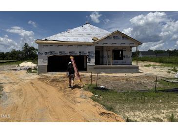 New construction of a single-Gathering home with builder carrying a ladder in the front of the house at 136 Tuskeegee Dr, Smithfield, NC 27577