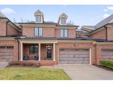 Charming brick townhouse featuring a two-car garage and welcoming front porch seating at 137 Cofield Cir, Durham, NC 27707