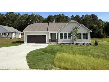 Charming one-story home with a brown garage door and a beautifully landscaped front yard at 171 Tulipfield Way, Benson, NC 27504