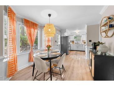 Bright dining area featuring a round table, woven pendant light, and large windows with vibrant orange curtains at 3541 E Jameson Rd, Raleigh, NC 27604