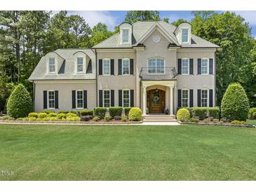 Stately two-story home with a brick facade, manicured lawn, black shutters, and charming dormer windows at 5112 Highbury Grove Ln, Fuquay Varina, NC 27526