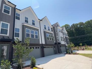 Modern townhouse exterior with gray and white siding and attached garages on a sunny day at 1006 Regalia Rd # 4, Durham, NC 27713