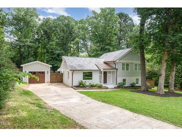 Charming home with a driveway leading to a detached garage, nestled amongst mature trees at 1209 Lanark Ct, Cary, NC 27511