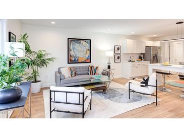 Bright living room with stylish gray sofa, modern art, and adjacent kitchen, perfect for entertaining at 1309 Hudson Ave # D12, Durham, NC 27705