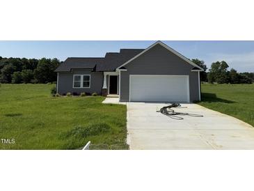 Charming single-story home featuring gray siding and a two-car garage on a green lot at 166 Coharie Dr, Lillington, NC 27546