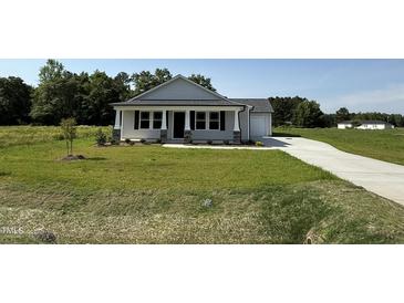 Charming single-story home with a well-manicured lawn and a covered front porch at 206 Coharie Dr, Lillington, NC 27546