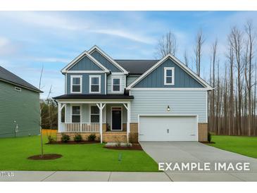 Charming two-story home with a manicured lawn, a welcoming porch, and a two-car garage at 412 Longleaf Glen Lane, Zebulon, NC 27597