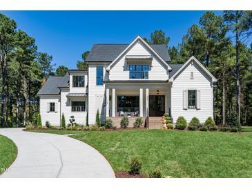 Beautiful two-story white home with a well-manicured lawn and lush landscaping on a sunny day at 476 Mollie Meadow Dr, Zebulon, NC 27597