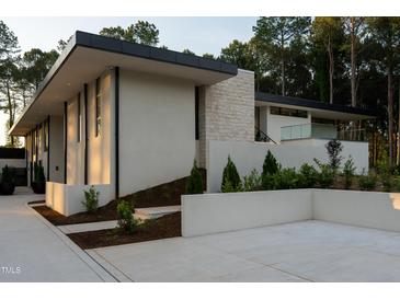 Contemporary home featuring clean lines, a stone accent wall, manicured landscaping and a flat roof design at 812 Stradella Rd, Raleigh, NC 27614