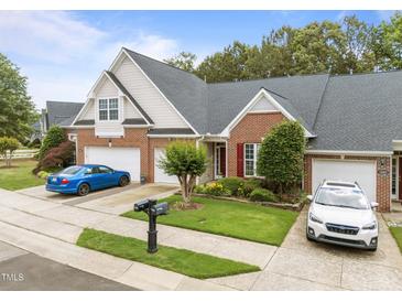 Charming brick townhome with a well-manicured lawn, colorful flower beds, and a two-car garage at 10404 Dapping Dr, Raleigh, NC 27614