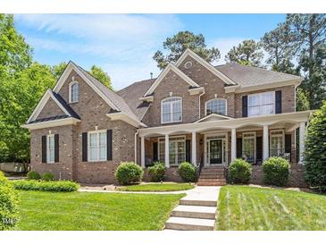 Charming two-story brick home boasts a well-manicured lawn and inviting covered front porch with stately white columns at 117 Arborhill Ln, Holly Springs, NC 27540