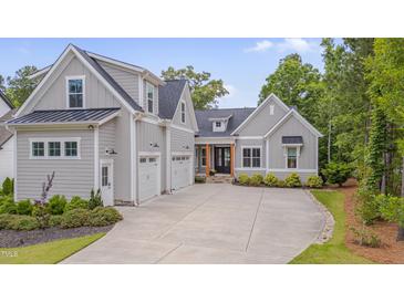 Beautiful gray home with three-car garage, stone pathway, black trim and mature landscaping at 14 Duck Bill Trl, Pittsboro, NC 27312