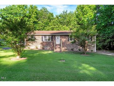 Charming brick home with a lush green front yard and mature trees offering shade at 3329 Broughton Dr, Durham, NC 27704