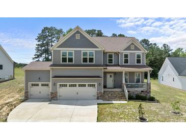 Charming two-story home featuring a welcoming front porch, three-car garage, and well-manicured lawn at 351 Lowery Ln, Benson, NC 27504