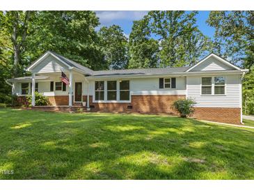 Charming brick and siding home featuring a covered porch and manicured lawn, located in a serene and tree-lined neighborhood at 418 S West St, Cary, NC 27511