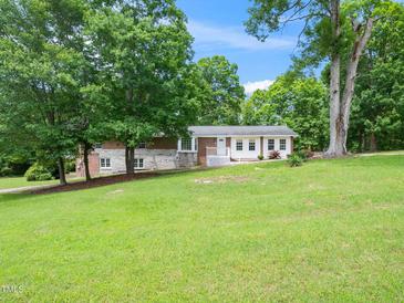 Charming single-story home with a combination brick and white exterior, surrounded by lush trees and a green lawn at 4605 Malor Dr, Wake Forest, NC 27587