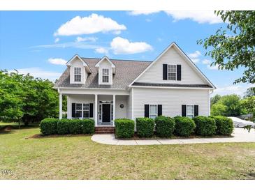 Charming two-story home featuring white siding, black shutters, and a welcoming front porch at 509 Spruce Meadows Ln, Willow Springs, NC 27592