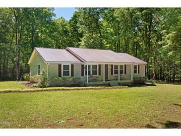 Charming single-story home with a metal roof and covered front porch nestled among trees at 560 Parker Creek Rd, Holly Springs, NC 27540