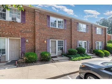 Brick townhome with purple shutters and small shrubs surrounding the front entrance to the property at 103 Coleridge Ct, Carrboro, NC 27510