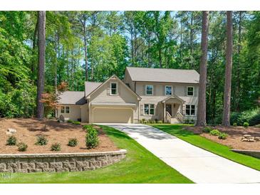 Charming two-story home with neutral siding, attached garage, and long driveway surrounded by lush trees at 11817 Coachmans Way, Raleigh, NC 27614