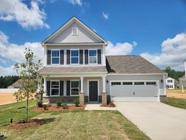 Charming two-story home with gray siding, black shutters, and a two-car garage under a clear blue sky at 142 Benson Village Dr # 82, Benson, NC 27504