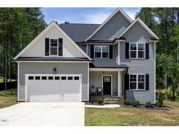 Charming two-story home with gray siding, black shutters, covered porch, and a spacious two-car garage at 220 Purslane Dr, Franklinton, NC 27525