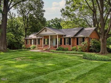 Charming brick home with a manicured lawn, mature trees and black shutters exudes curb appeal at 2228 Walker Ave, Burlington, NC 27215