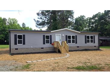 Charming single-story home features gray siding, black shutters, a welcoming front porch and lovely landscaping at 2668 Bodie Currin Rd, Oxford, NC 27565