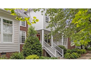 Charming two-story home with a front porch, red front door, landscaped yard, and brick and siding exterior at 3923 Napa Valley Dr, Raleigh, NC 27612