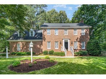 Stately brick two-story home featuring manicured lawn, mature trees, and classic architectural details at 4020 Gumleaf Dr, Apex, NC 27539