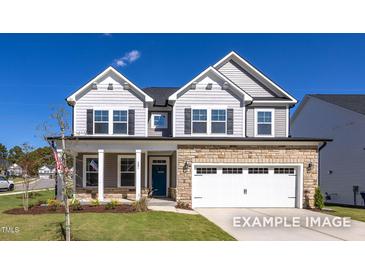 Charming two-story home featuring stone accents, a two-car garage, and a well-maintained front lawn at 408 Longleaf Glen Lane, Zebulon, NC 27597