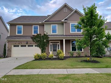 Two-story home featuring a manicured lawn, attached garage, and charming front porch at 617 Hiddenbrook Dr, Durham, NC 27703