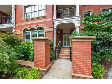 Charming brick building entrance featuring a covered porch, stone pillars, and landscaped greenery at 710 Independence Pl # 103, Raleigh, NC 27603