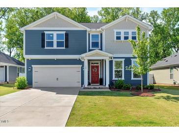 Charming two-story home with a well-manicured lawn, attached garage and inviting red front door at 128 Potomac River St, Garner, NC 27529