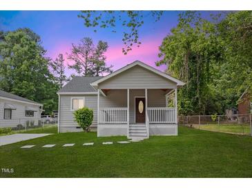 Charming home featuring a cozy front porch and well-maintained lawn at 128 W Parker St, Henderson, NC 27536
