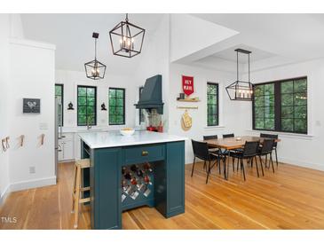 Bright kitchen with white cabinets, a contrasting emerald island, and a dining area with hardwood floors at 1503 Hollywood St, Durham, NC 27701