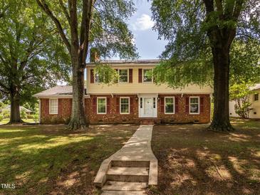 Traditional two-story home with red brick and yellow siding, surrounded by mature trees at 223 Shadowbrook Dr, Burlington, NC 27215