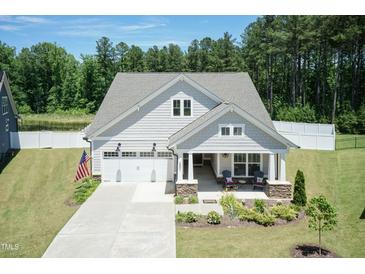 Charming home with a well-manicured lawn, American flag, and a covered porch for relaxing at 2501 Impulsion Dr, New Hill, NC 27562