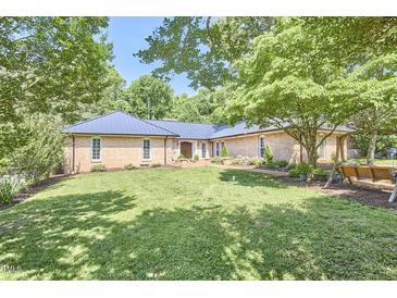 Charming brick home featuring a manicured lawn and mature trees providing ample shade at 423 N Cameron St, Hillsborough, NC 27278
