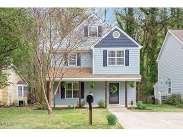 Charming two-story home with light blue siding, black shutters, front porch, and landscaped yard at 4520 Timberhurst Dr, Raleigh, NC 27612