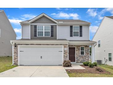 Two-story home with a two-car garage, stone accents, and vinyl siding for a modern look at 717 Little Patch St, Zebulon, NC 27597