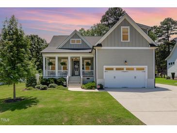 Charming home boasts a well-manicured lawn, a welcoming front porch, and an attached two-car garage at 816 Trumpet Vine Ct, Wendell, NC 27591