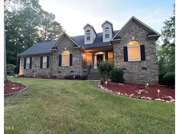 Charming brick home with dormers, manicured lawn, and landscape lighting at 1016 Luminary Ln, Willow Springs, NC 27592