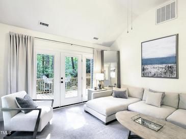 Bright living room with a white sectional sofa and French doors to the outdoor deck at 107 Long Shadow Ln, Cary, NC 27518