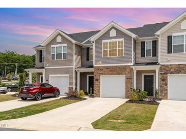 Townhome exterior with neutral siding, brick accents, individual driveways, and attached garages at 1230 Adrian Ct, Mebane, NC 27302